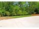 Large backyard with lush greenery, a concrete patio, and mature trees at 3934 Old Chapel Hill Rd, Durham, NC 27707
