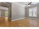 An airy bedroom features natural light from a window, a ceiling fan, and beautiful wood floors at 3934 Old Chapel Hill Rd, Durham, NC 27707