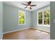 An airy bedroom with hardwood floors, a ceiling fan, and two windows at 3934 Old Chapel Hill Rd, Durham, NC 27707