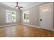An airy bedroom features natural light from two windows and a door, with a ceiling fan and beautiful wood floors at 3934 Old Chapel Hill Rd, Durham, NC 27707