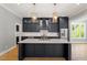 Modern kitchen with sleek, dark cabinets, quartz countertop island, and stainless-steel appliances at 3934 Old Chapel Hill Rd, Durham, NC 27707