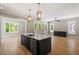A modern kitchen island features dark cabinets, granite countertops and stainless steel appliances, with wood floors at 3934 Old Chapel Hill Rd, Durham, NC 27707