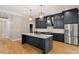 A modern kitchen features dark cabinets with gold hardware, marble backsplash, and stainless steel appliances at 3934 Old Chapel Hill Rd, Durham, NC 27707