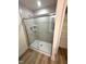 Modern tiled shower with glass doors, shelving, and chrome fixtures at 408 La Maison Ave # 3, Wendell, NC 27591