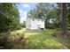 Back of home with a lush green backyard, mature trees, and patio area at 409 Glaive Dr, Durham, NC 27703