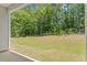 A covered back patio looks out over a large lawn and a natural area of trees at 418 Ivy Bank Dr, Angier, NC 27501