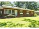 Charming brick home featuring mature landscaping, a manicured lawn, a bright white front door, and double-hung windows at 452 N Main St, Wendell, NC 27591