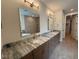 Bathroom featuring double sinks, granite countertops, and a large framed mirror at 48 Firefly Ln, Fuquay Varina, NC 27526