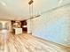 Open-concept living space with modern light fixture, hardwood floors, island and textured accent wall at 48 Firefly Ln, Fuquay Varina, NC 27526