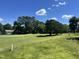 Scenic view of a lush green golf course with mature trees and a glimpse of a house in the background at 4917 Harbour Towne Dr, Raleigh, NC 27604