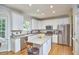 Well-lit kitchen featuring stainless steel appliances, an island with seating, and white cabinets at 5328 Willow Cry Ln, Raleigh, NC 27613