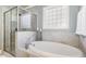 Relaxing bathroom featuring a soaking tub with tile surround and a frosted glass block window providing natural light at 5629 Clearsprings Dr, Wake Forest, NC 27587