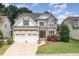 Charming two-story home featuring a stone facade, a three-car garage, and a well-manicured lawn at 5629 Clearsprings Dr, Wake Forest, NC 27587