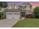 Charming two-story home featuring a stone facade, a three-car garage, and a well-manicured lawn at 5629 Clearsprings Dr, Wake Forest, NC 27587