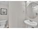 A sleek powder room with a pedestal sink, round mirror, toilet and light grey walls at 5824 Cameo Glass Way, Raleigh, NC 27612