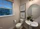 Charming half bathroom with decorative wallpaper, a pedestal sink, and a window with natural light at 5904 Dunzo Dr, Raleigh, NC 27617