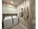 Laundry room with white washer and dryer, upper cabinets, and stylish wallpaper for a modern touch at 5904 Dunzo Dr, Raleigh, NC 27617