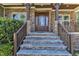 Close-up of the home's entrance featuring stone columns, wood railing, stone steps, and a solid wood front door at 6332 Mountain Oaks Way, Wake Forest, NC 27587