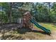 Backyard playground featuring a playhouse, slide, and climbing wall, surrounded by mature trees at 6332 Mountain Oaks Way, Wake Forest, NC 27587