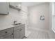 Well-lit laundry room with gray cabinetry, patterned tile flooring, and a stainless steel sink at 703 E Markham Ave, Durham, NC 27701