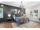 Chic bedroom with a dark accent wall, stylish chandelier, plush bedding, and ample natural light at 703 E Markham Ave, Durham, NC 27701