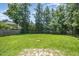 Large, green backyard with mature trees along the perimeter, enclosed by a wooden privacy fence at 709 Woodgreen Dr, Durham, NC 27704