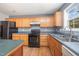 Up-close view of kitchen with wood cabinets and black appliances, including stove and dishwasher at 709 Woodgreen Dr, Durham, NC 27704