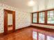 Comfortable bedroom with vintage floral wallpaper, hardwood floors, and multiple windows at 714 Spring Ln, Sanford, NC 27330