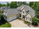 Aerial view of a tan two story home with a three car garage, large driveway, and mature landscaping at 812 Bear Tree Crk, Chapel Hill, NC 27517