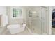 Bright bathroom featuring soaking tub with glass shower, and a large window with frosted glass block detail at 812 Bear Tree Crk, Chapel Hill, NC 27517