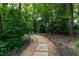 Picturesque stone path leading to an outdoor seating area, set amongst lush greenery and mature trees at 8604 Timberwind Dr, Raleigh, NC 27615