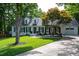 Beautiful home featuring a manicured lawn, mature tree, black shutters, white siding, and a driveway leading to an attached garage at 8604 Timberwind Dr, Raleigh, NC 27615