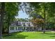 A well manicured front lawn frames a charming two-story home featuring white siding, black shutters, and mature trees at 8604 Timberwind Dr, Raleigh, NC 27615