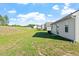 This backyard features green grass, some weeds, and a view of neighboring houses and a bright partly cloudy sky at 87 Royal Meadow Dr, Angier, NC 27501