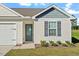 Close-up of a charming home's exterior showcasing gray accents, lush landscaping, and a welcoming front door at 87 Royal Meadow Dr, Angier, NC 27501
