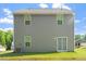 Back view of a house with gray siding, showing multiple windows, a sliding glass door, and a grassy lawn at 94 Taverners Ln, Angier, NC 27501