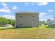 Grassy backyard featuring a two-story home with gray siding, complemented by blue skies and green trees at 94 Taverners Ln, Angier, NC 27501