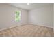An empty bedroom with a neutral carpet and natural light streaming through a window with blinds at 94 Taverners Ln, Angier, NC 27501