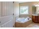 Bathroom corner soaker tub with tile surround, a bright window and tile flooring at 9701 Corktree Ct, Wake Forest, NC 27587