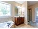 Bathroom featuring a jacuzzi tub, vanity with storage, and a walk-in shower with glass door at 9701 Corktree Ct, Wake Forest, NC 27587