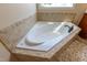 This corner jacuzzi tub boasts a tile border and dark hardware faucet at 9701 Corktree Ct, Wake Forest, NC 27587