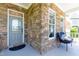 Charming stone front porch with a gray front door and a comfy blue chair at 9701 Corktree Ct, Wake Forest, NC 27587