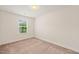 A simple bedroom with tan carpet, white walls, and a bright window at 1137 Amber Shadow Dr, Durham, NC 27703