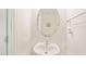 A quaint powder room with a pedestal sink, an oval mirror, and bright white walls at 1137 Amber Shadow Dr, Durham, NC 27703