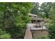 The exterior of the home is set amongst lush greenery, a gravel patio, and a wooden bridge at 1320 Shepherd St, Durham, NC 27707