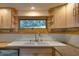 This kitchen sink area features wooden cabinets, granite counters, and a window with a wooded view at 1320 Shepherd St, Durham, NC 27707