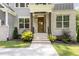 Inviting front porch with brick columns, a decorative front door, and manicured landscaping at 1417 Westmoreland Dr, Raleigh, NC 27612
