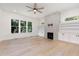 Spacious living room with hardwood floors, stone fireplace, built-in shelves, and large windows at 1417 Westmoreland Dr, Raleigh, NC 27612
