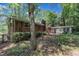 Backyard of a brick home featuring mature trees and partial landscaping with an attached home at 1500 Lakeside Dr, Garner, NC 27529