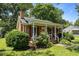 Well-maintained brick home featuring a covered porch, classic shutters, and manicured landscaping at 1542 W Davis St, Burlington, NC 27215